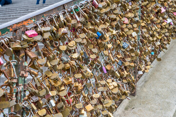 Love locks adorn a bridge in the heart of a bustling city during a sunny day