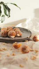 Mini doughnuts on the plate with baking paper on a table with crumbs around. 