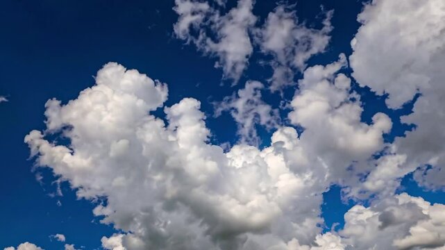 A stunning 4K cinemagraph time-lapse capturing fluffy, puffy white cirrus and cirrostratus clouds drifting gracefully across a vibrant, clear blue sky. 