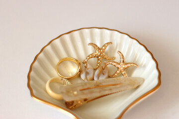 White shell shaped trinket with gold and beige accessories. Selective focus, white background.
