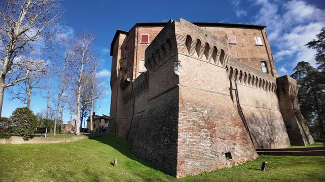 Medieval fortress of Dozza castle rising majestically on a green hill in Emilia Romagna, Italy, showcasing its brick walls and defensive structures against a blue sky