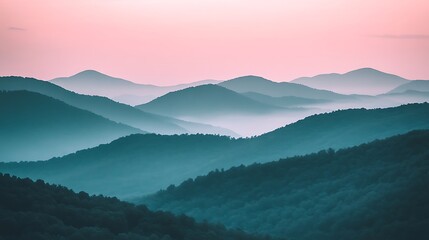 A misty mountain range with layers of hills fading into the distance and the first light of day