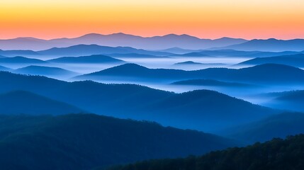 A misty mountain range with layers of hills fading into the distance and the first light of day