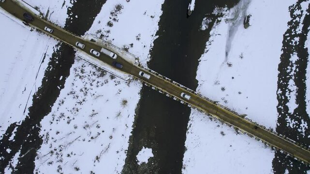 Aerial drone straight down shot showing bridge passing over frozen lidder river covered in snow with vehicles passing over it to get to Phelgam, Srinagar in Kashmir paradise on earth