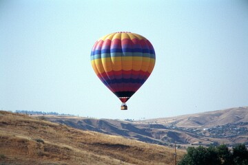 Obraz premium Colorful hot air balloon floats over rolling hills