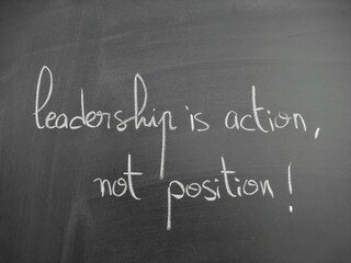 Obraz premium Inspirational quote on leadership written in handwriting on a chalkboard expressing thoughtful guidance and motivational wisdom in an educational setting. Leadership is action not position