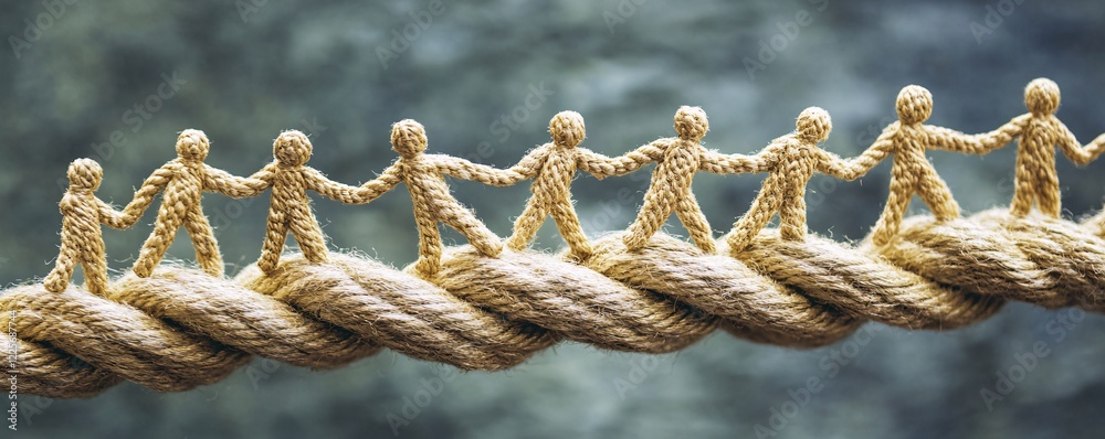 Poster figurines standing hand in hand on a rope bridge, symbolizing unity and collaboration