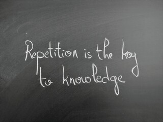 Obraz premium Handwritten quote on blackboard emphasizing repetition as key to acquiring knowledge - Repetition is the key to knowledge