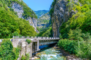 Fototapeta premium Automobile bridge across the mountain river in Abkhazia against the background of the sky in the valley of the Caucasus Mountains and Rocks. Road to the in Yupsharsky Canyon.Trip, travel on vacation
