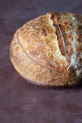 Fresh homemade sourdough bread with whole grain flour on brown background. Healthy food.