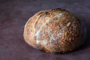 Fresh homemade sourdough bread with whole grain flour on brown background. Healthy food.