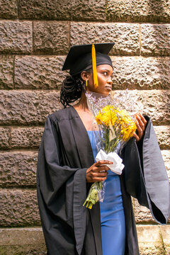 Black woman on her graduation day holding yellow flowers