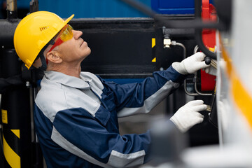 Worker in uniform operator controls manual levers of crane truck on construction site