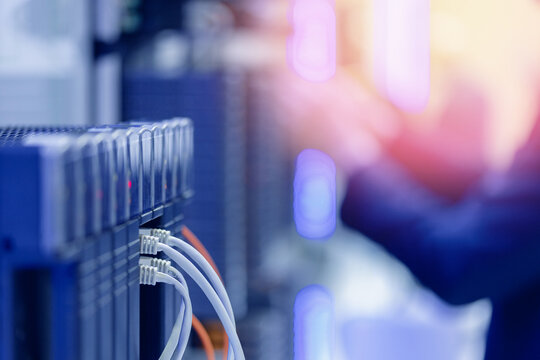 Data center server room with network cables and blurred technician in background