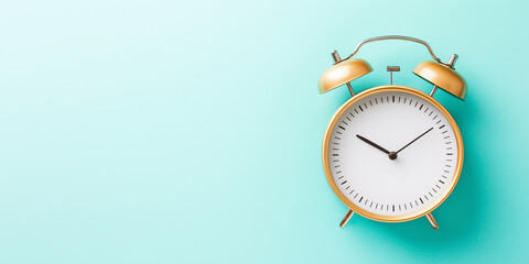 A stylish golden alarm clock with a white face sits against a turquoise background, combining vintage charm with a modern pastel aesthetic.  