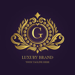 Gold Letter 'G' Logo with Ornamental Patterns and Floral Motifs on Purple  
