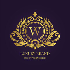 Gold Letter 'W' Logo with Ornamental Patterns and Floral Motifs on Purple  
