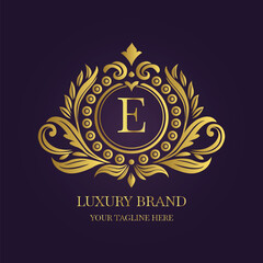 Gold Letter 'E' Logo with Ornamental Patterns and Floral Motifs on Purple  
