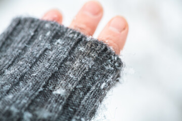 Close up of grey wool knitted fabric glove with snowflakes, winter day