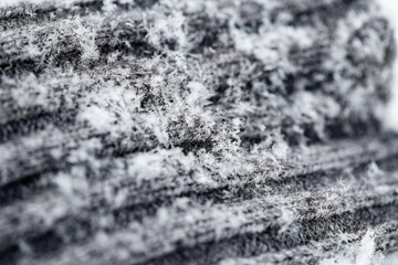 Close up of grey wool knitted fabric glove with snowflakes, winter day