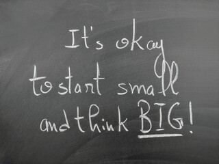 Obraz premium Inspirational handwritten quote on chalkboard advocating starting small and thinking big, emphasizing motivation and growth