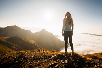 Female hiker enjoying breathtaking sunset view over sea of clouds in the pyrenees mountains