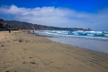 A beach with a few people walking on it