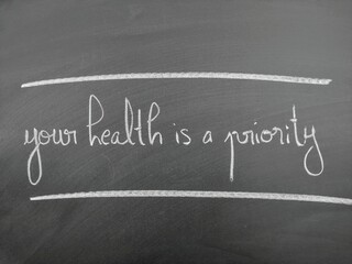 Handwritten message on a chalkboard stating 'Your health is a priority' with minimal design.