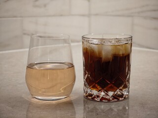 Two elegant glasses showcasing contrasting beverages on a polished countertop in soft lighting