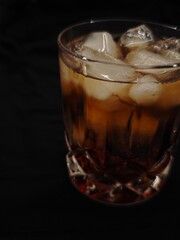 Refreshing iced drink in a crystal glass resting on a decorative coaster in cozy dim light