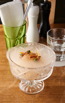 An eye-catching sorbet is served in a crystal glass, garnished with colorful elements. The table features various dining accessories, creating an inviting atmosphere