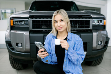 Saleswoman drinking coffee and using smartphone in front of pickup truck © nazariykarkhut