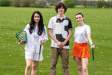 Young golfers standing on a golf field with brassies in hands
