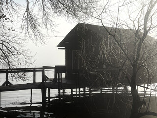 River merging with fog and a small wooden house against the backdrop of dim sun rays. Beautiful...