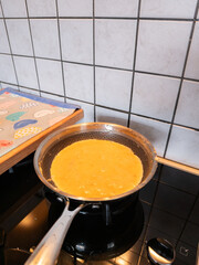 A saucepan on gas fire with eggs, cooking an omelette. Simple but yummy dish. The gas fire is on. Healthy food cooking, home made healthy dinner. Fresh.
