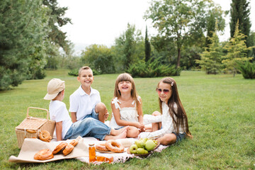 Happy cheerful kids having picnic on green grass lawn together outdoors. Happiness. Friendship.