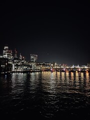 Obraz premium Night view of the City of London, with illuminated skyscrapers and historic buildings. Perfect for projects on urban nightlife, cityscapes, and the contrast between modern and historic architecture.