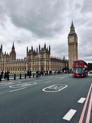 View of Westminster Bridge, Parliament, and Big Ben with a classic red double-decker bus crossing. Iconic London scene, perfect for projects on tourism, British landmarks, and cityscapes.
