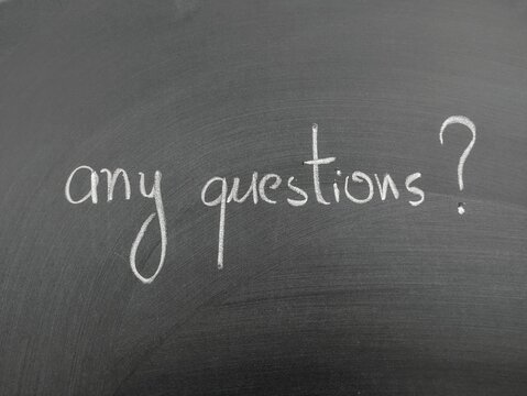 Handwritten phrase any questions written in white chalk on a blackboard background