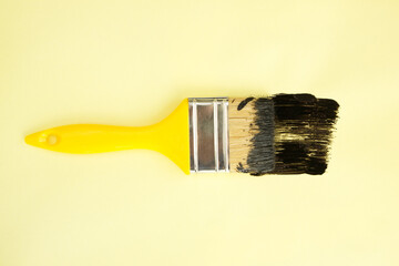 Paint brush with black paint on yellow background