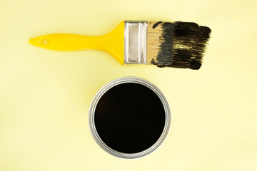 Paint brush with black paint on yellow background