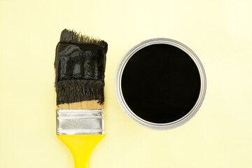 Paint brush with black paint on yellow background