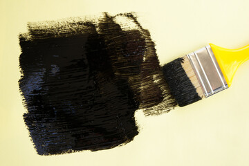 Paint brush with black paint on yellow background