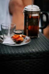Woman in white robe enjoys tea on terrace with stunning view of snow-capped mountains in winter sunset