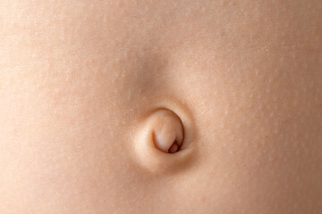 Close-up of a baby navel with delicate skin in soft lighting, highlighting the texture.