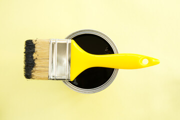 Paint brush with black paint on yellow background