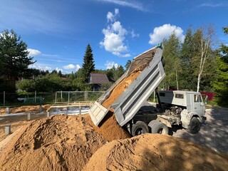 truck unloading sand at construction site, rural landscape