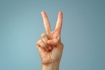 Victory hand gesture against a blue background, minimalistic close-up of fingers forming a peace sign, symbolic expression of positivity and triumph, clean and modern composition

