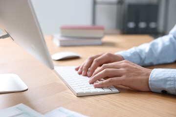 Fototapeta premium Man working on computer at wooden desk in office, closeup