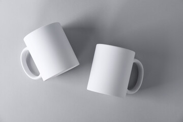 Two blank white mugs on light background, top view. Mockup for design